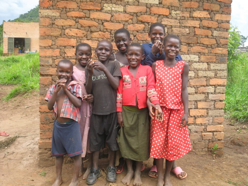 A group of children standing together against a brick wall outside their school.